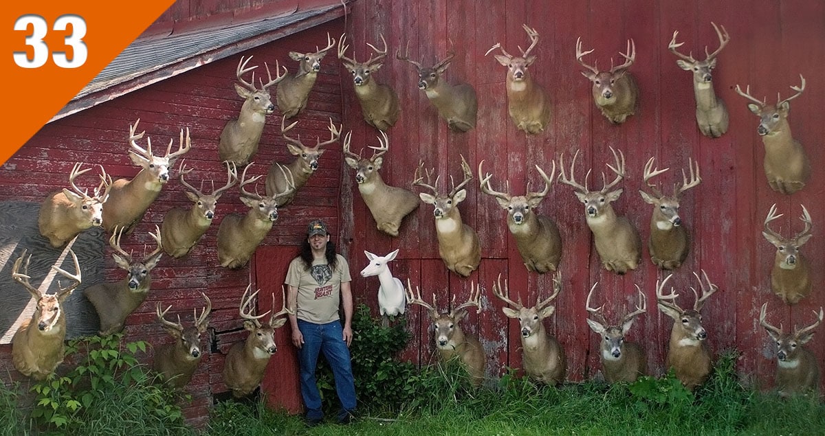 Photo of Dan Infalt with a barn wall full of big, mature bucks.